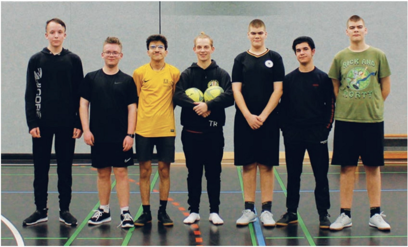 Das inklusive Fußball-Team des HTB Sieben Menschen mit und ohne Behinderung und im Sport-Dress stehen nebeneinander, einer in der Mitte hält 2 Fußbälle im Arm