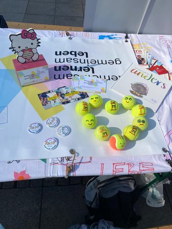 Auf eienm weißen bemalten Tischtuch liegen Tennisbälle und anderes von Pro Inklusion Hamburg